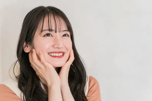 両手で顔を支え、微笑む女性